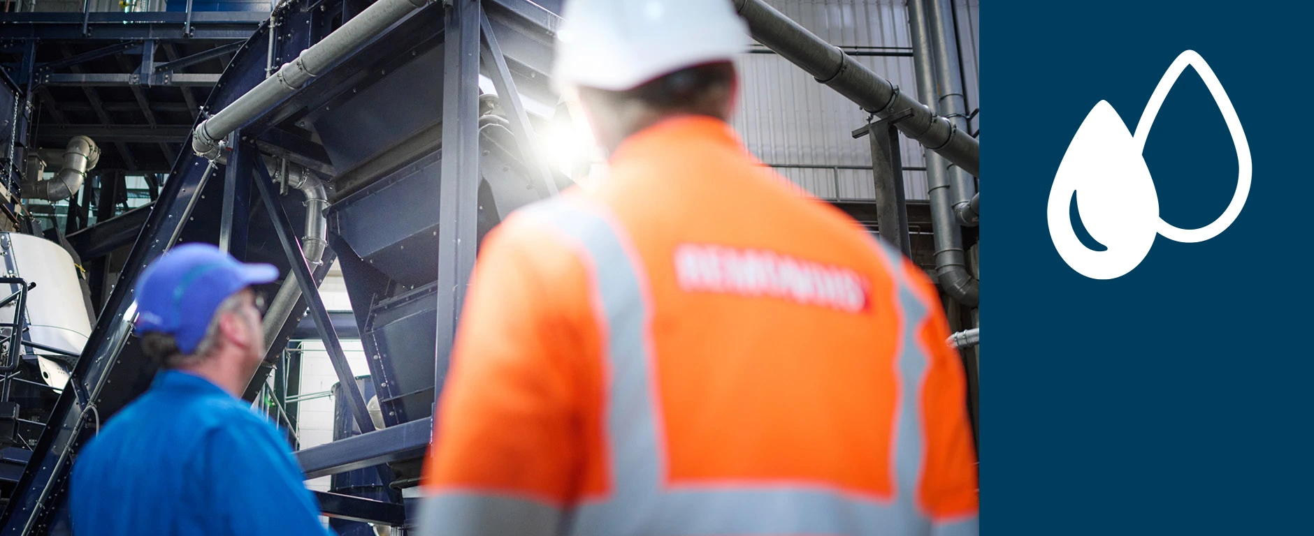 Zwei REMONDIS Mitarbeiter stehen vor einer Anlage in einer Industriehalle