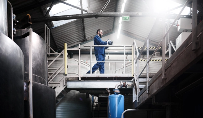 Mann in blauer Schutzkleidung geht durch eine Industriehalle