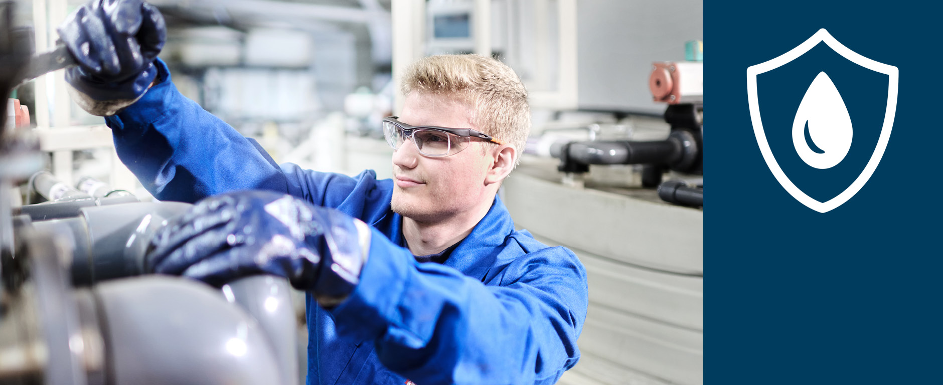 Ein Mitarbeiter mit Schutzbrille und Gummihandschuhen bedient einen Hebel an einer Anlage.