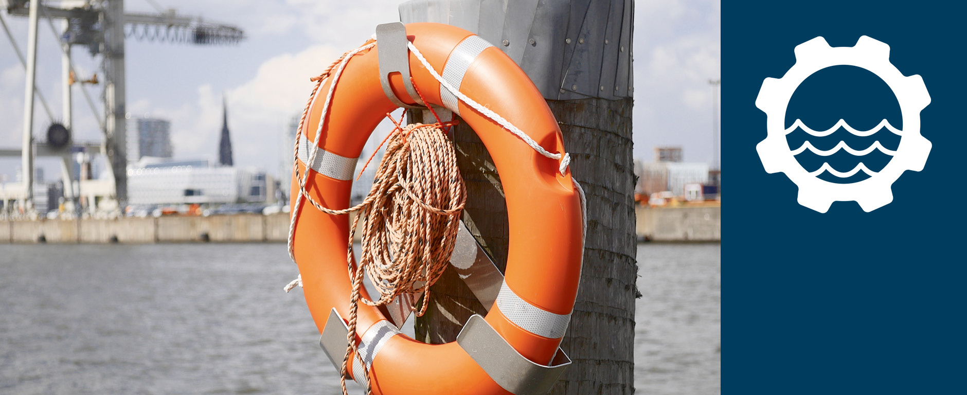 Foto vom Hamburger Hafen mit Rettungsring im Vordergrund und einem Ladekran im Hintergrund